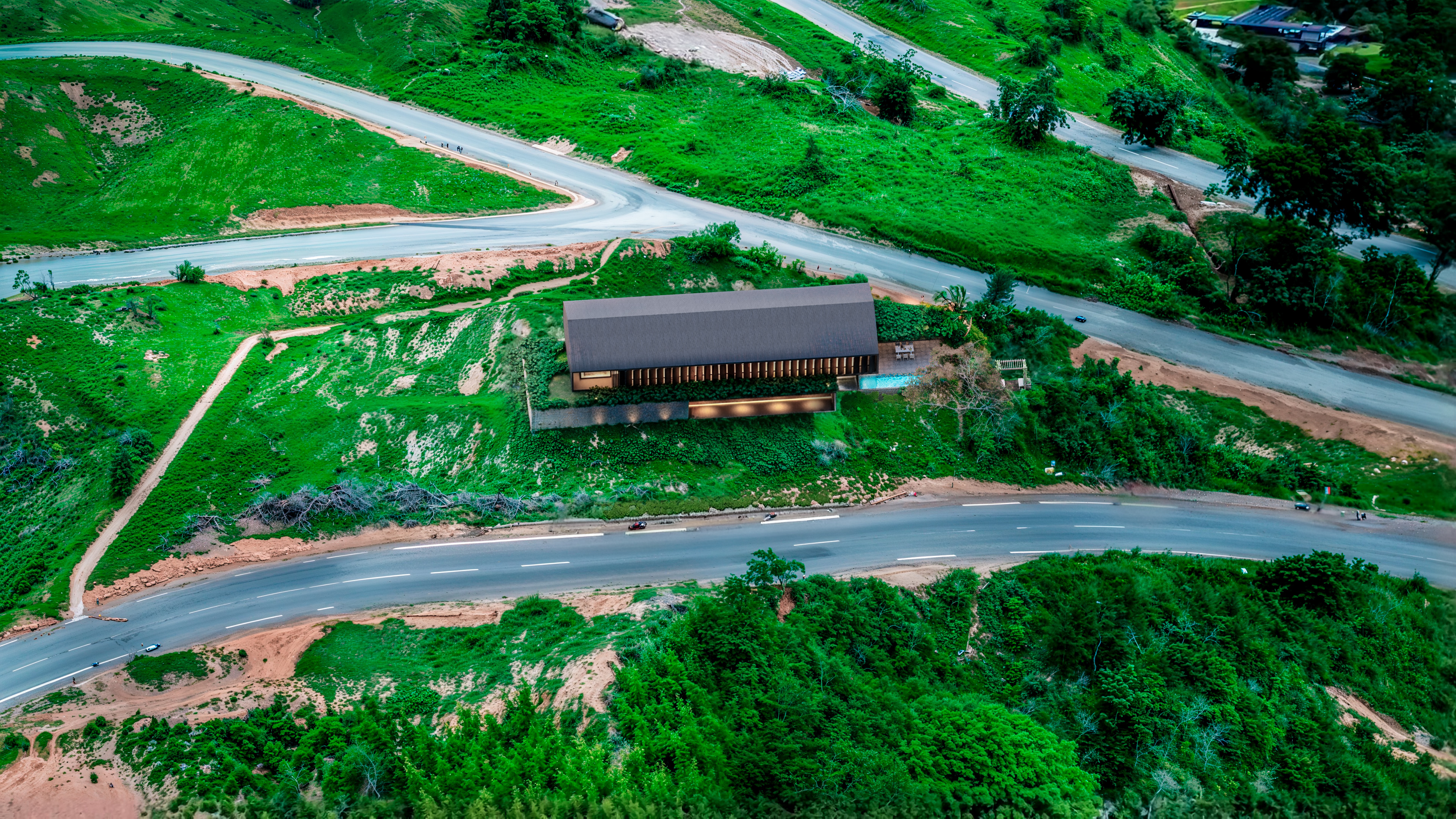 Vista aérea da Casa LG20 implantada na encosta verde em Araras, Petrópolis